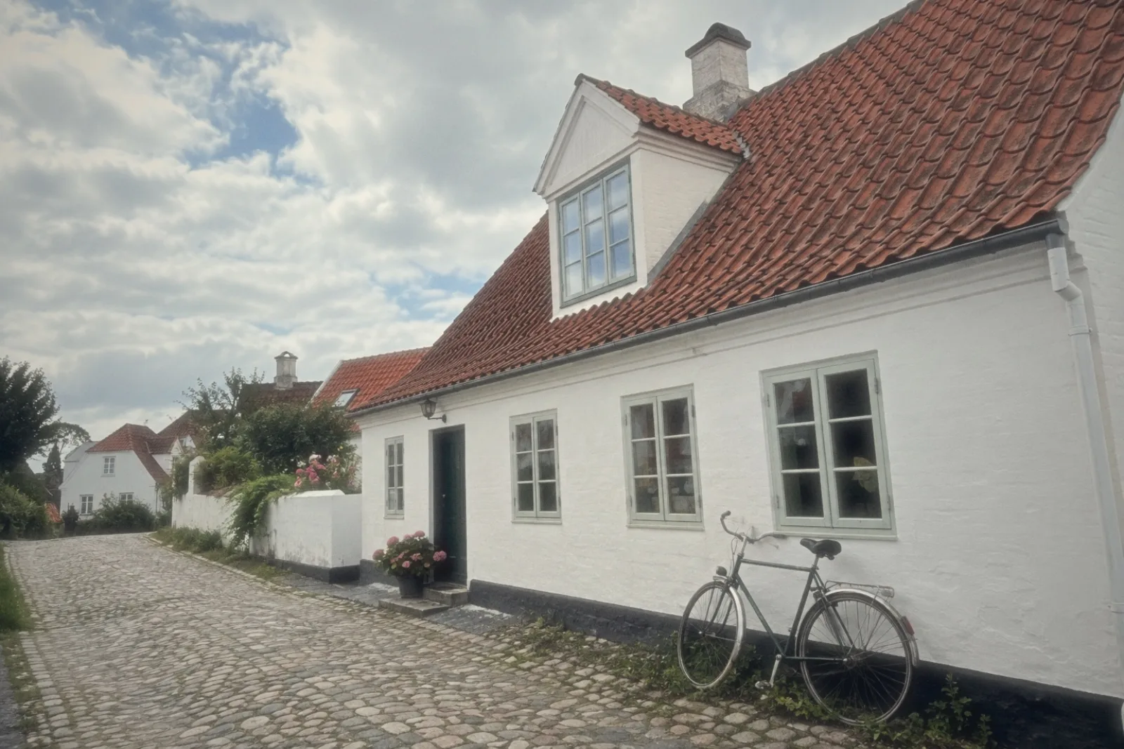 A white house with a red tiled roof and a bicycle by the door, shot on the CLASSIC 82