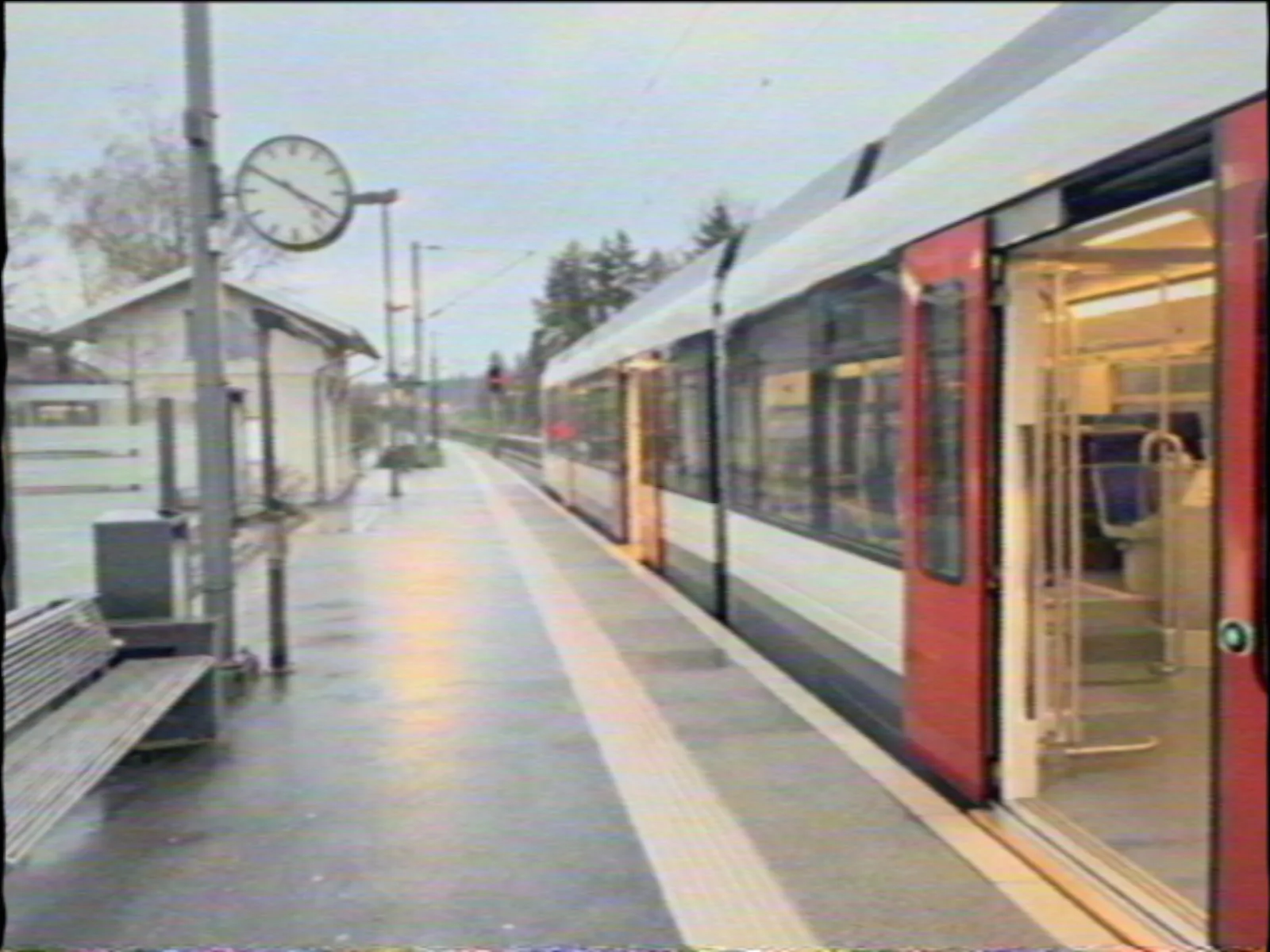 A train waiting at a small station platform on a grey day, shot on the REPORTER 76